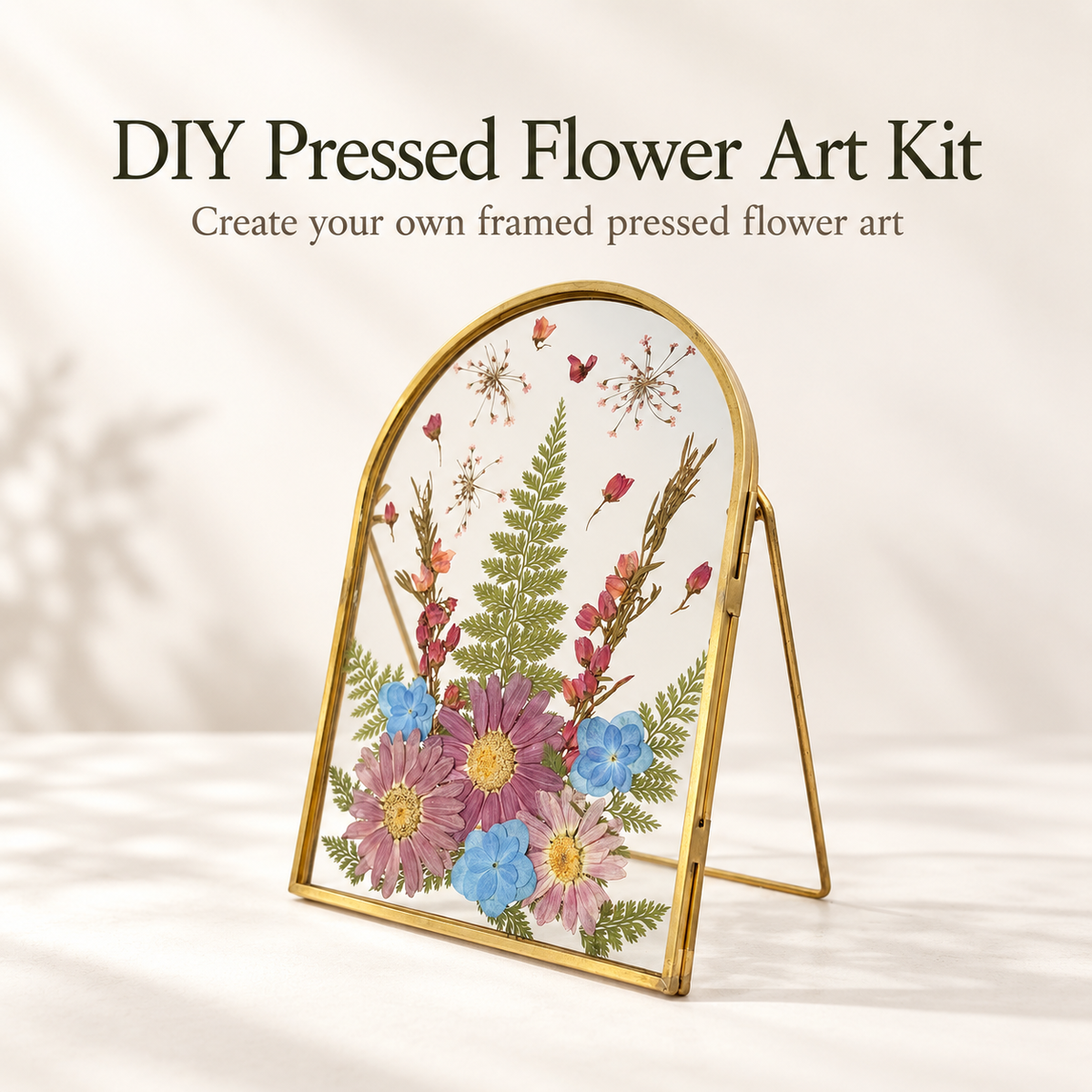 DIY Pressed Flower Art Kit with a gold-framed arch stand holding pressed botanical artwork, shown on a soft beige background with the text 'DIY Pressed Flower Art Kit' above it.