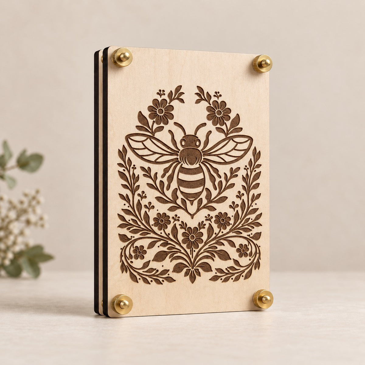 Laser-engraved wooden flower press featuring a detailed bee surrounded by floral vines and blossoms, finished with brass hardware on light maple wood.
