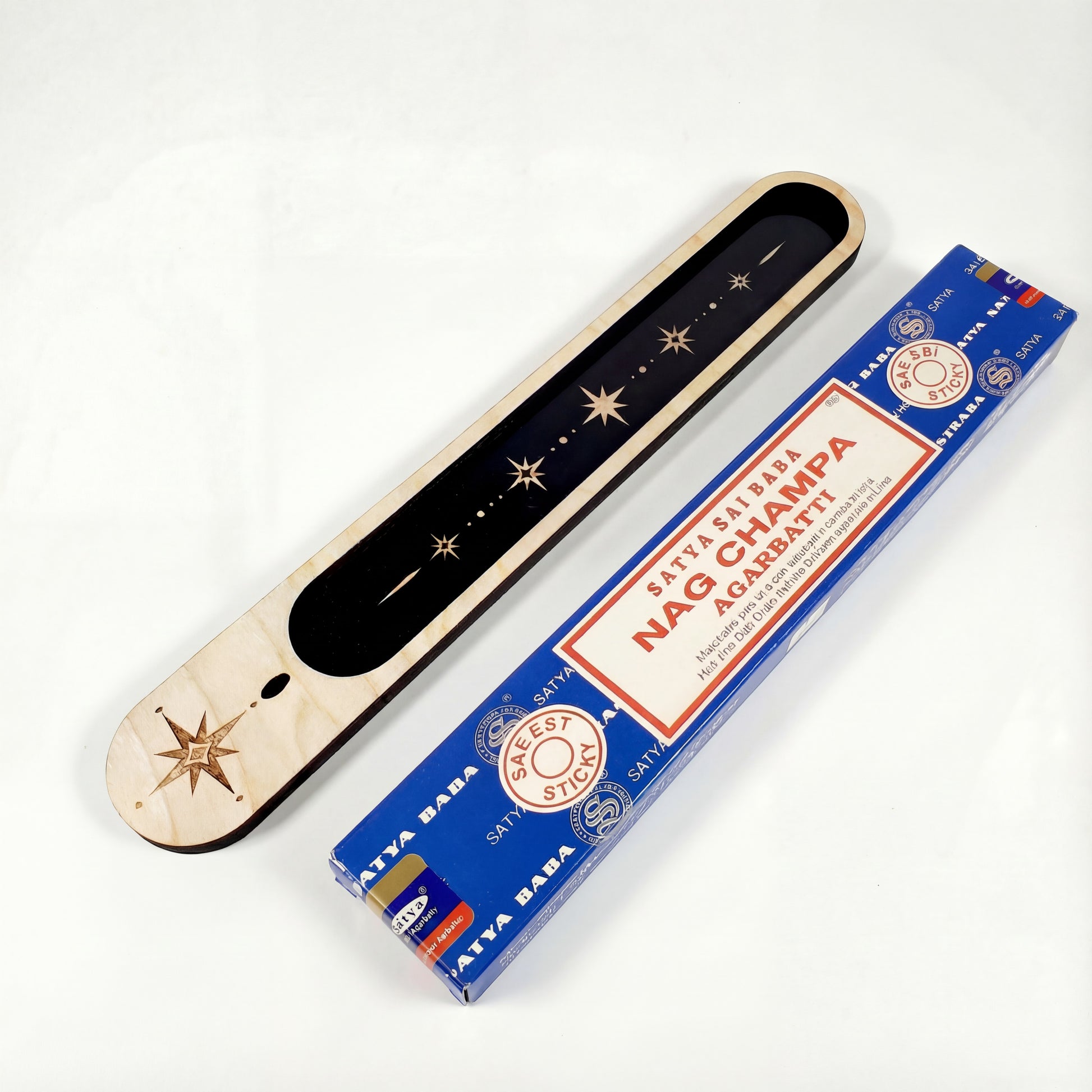 Wooden celestial incense holder with black inlay and star design shown next to a box of Nag Champa incense sticks on a white background.