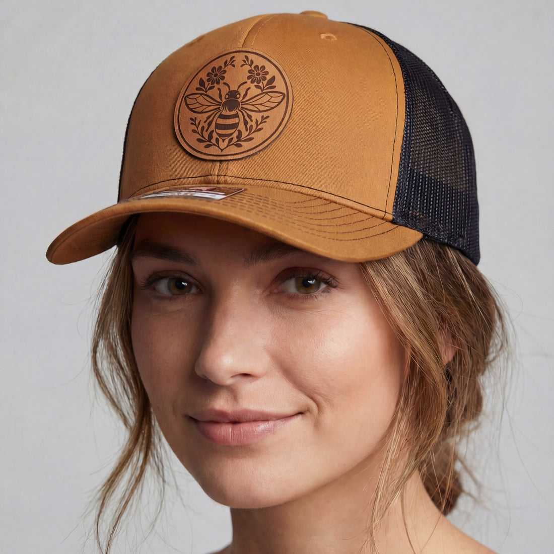 Woman wearing a brown and black cap with a logo on a gray background