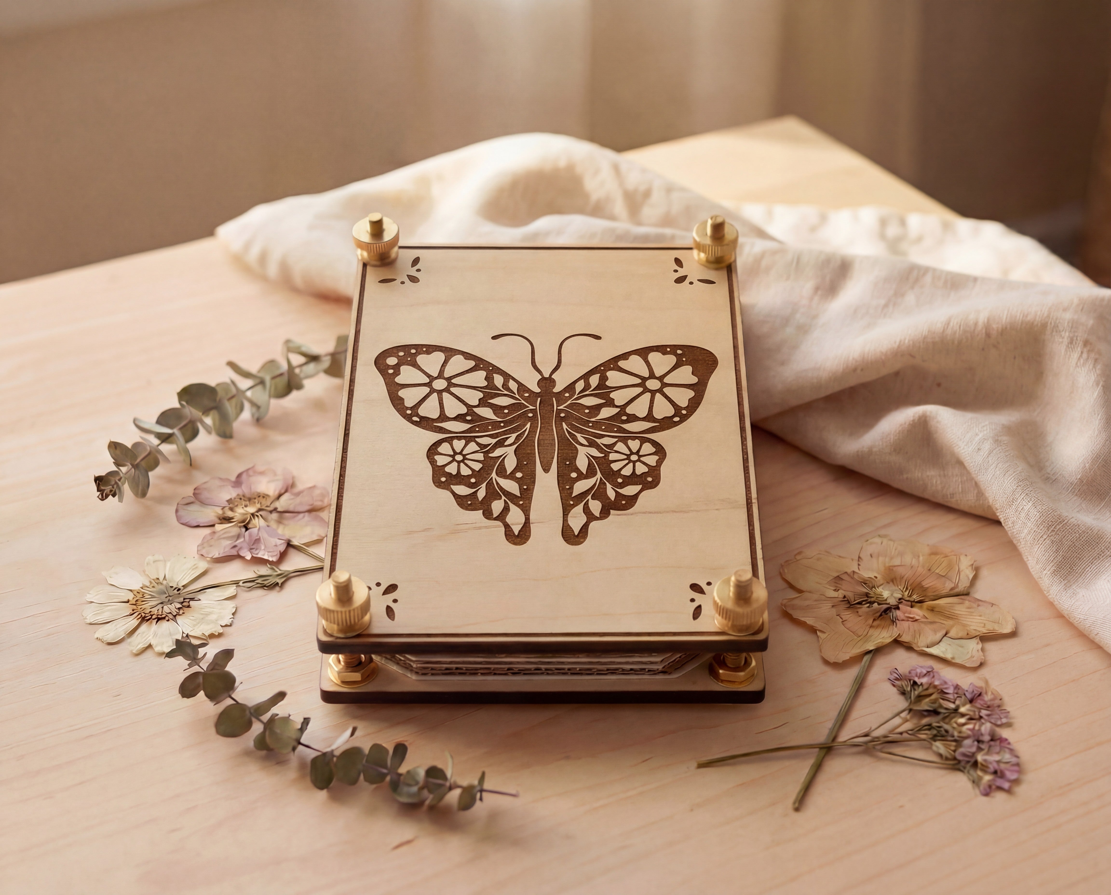 Handmade wooden flower press with laser-cut butterfly design and brass screw hardware, styled on a light wood table with eucalyptus sprigs and pressed wildflowers; eco-friendly botanical press for drying flowers, nature-inspired home decor, and a thoughtful gift for gardeners, plant lovers, and crafters.