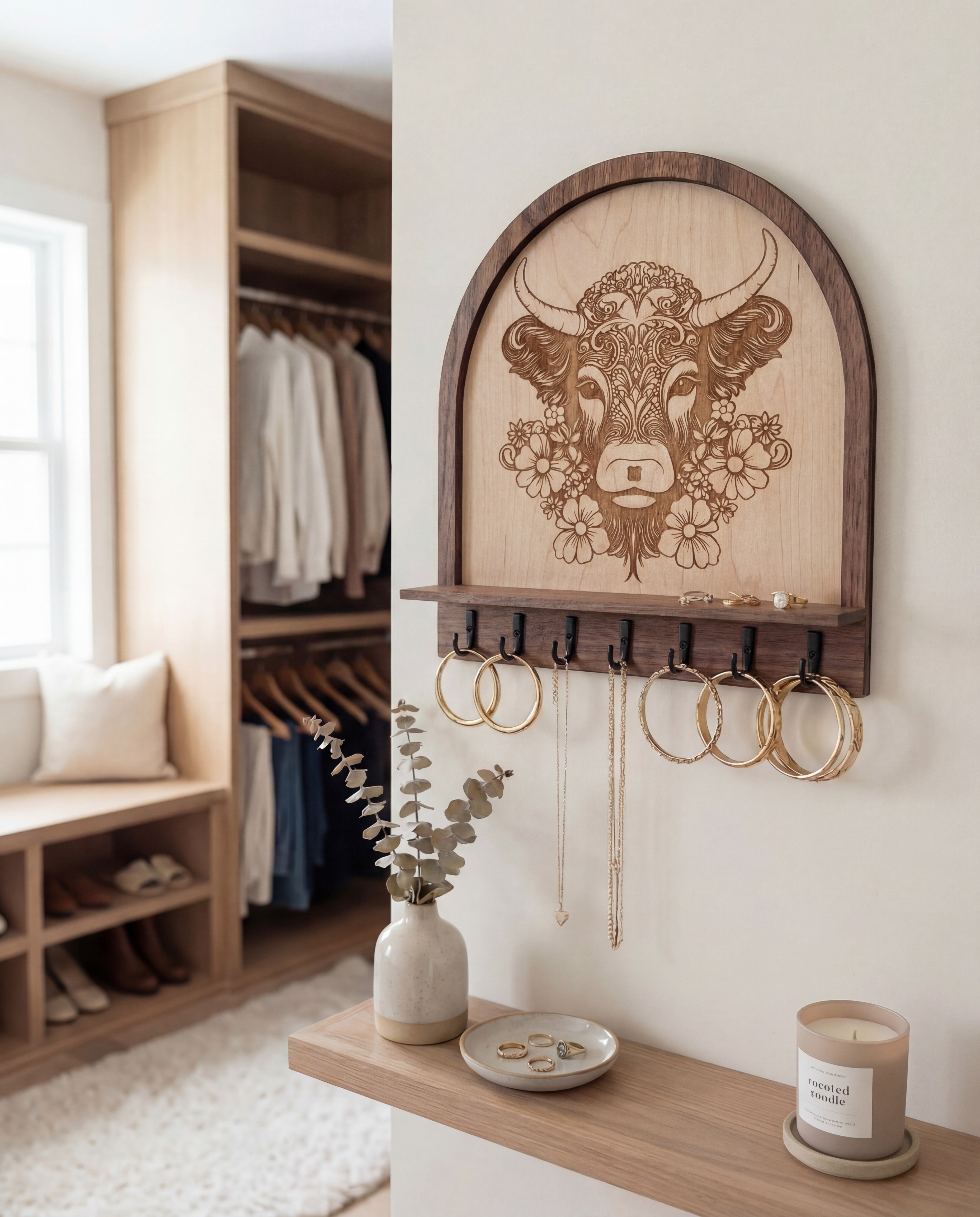Laser engraved floral highland cow wood wall organizer with shelf and hooks, shown as a key and jewelry holder with hoop earrings and necklaces hanging in a neutral farmhouse-style entryway.