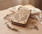 Handmade 4x6 maple flower press with brass hardware and original “Gather the little moments” engraved design, styled on a light wood table with linen cloth, eucalyptus sprigs, and pressed flowers.