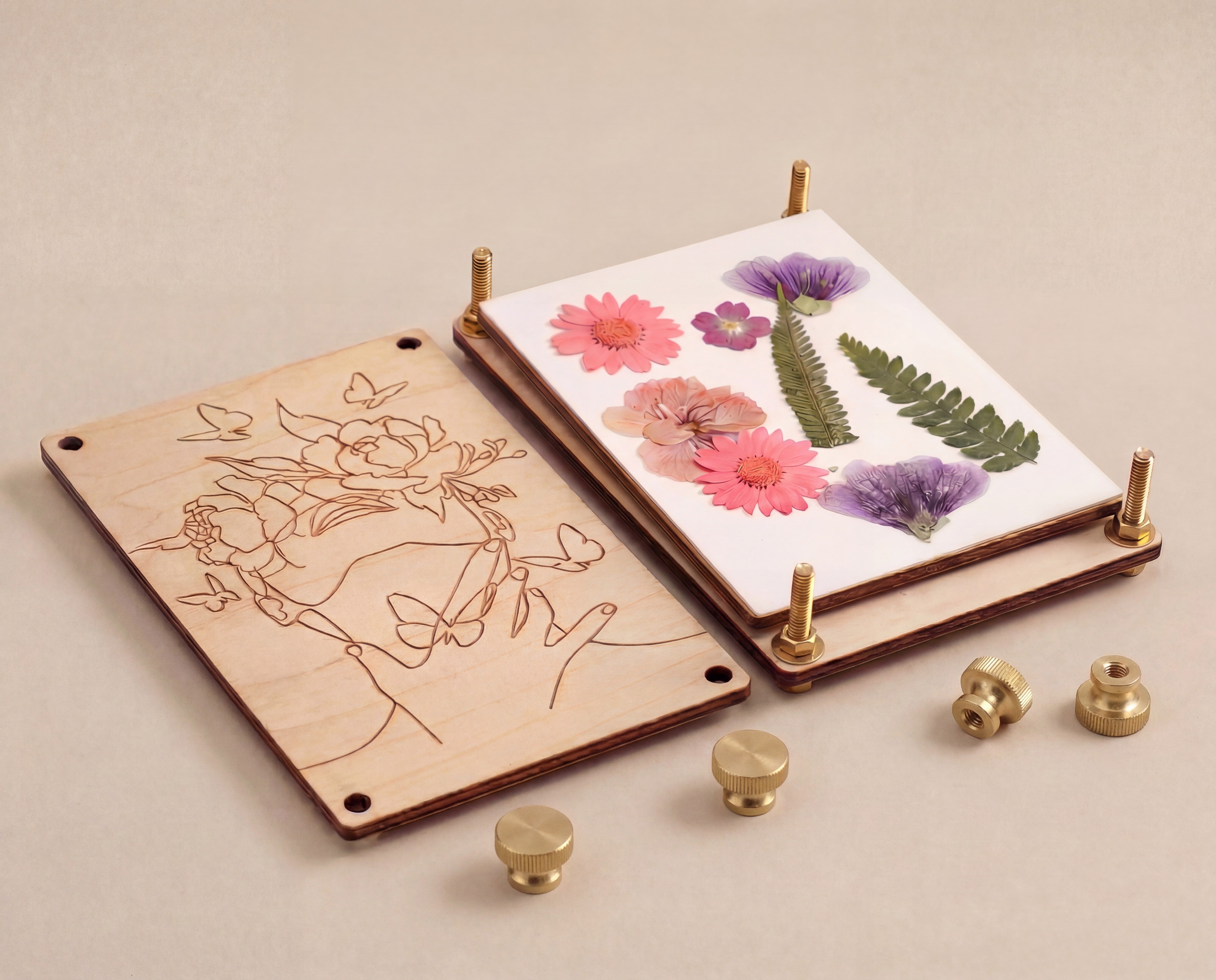 Handmade 4x6 maple wood flower press shown open with pressed flowers and fern, brass bolts and knurled thumb nuts beside it. 