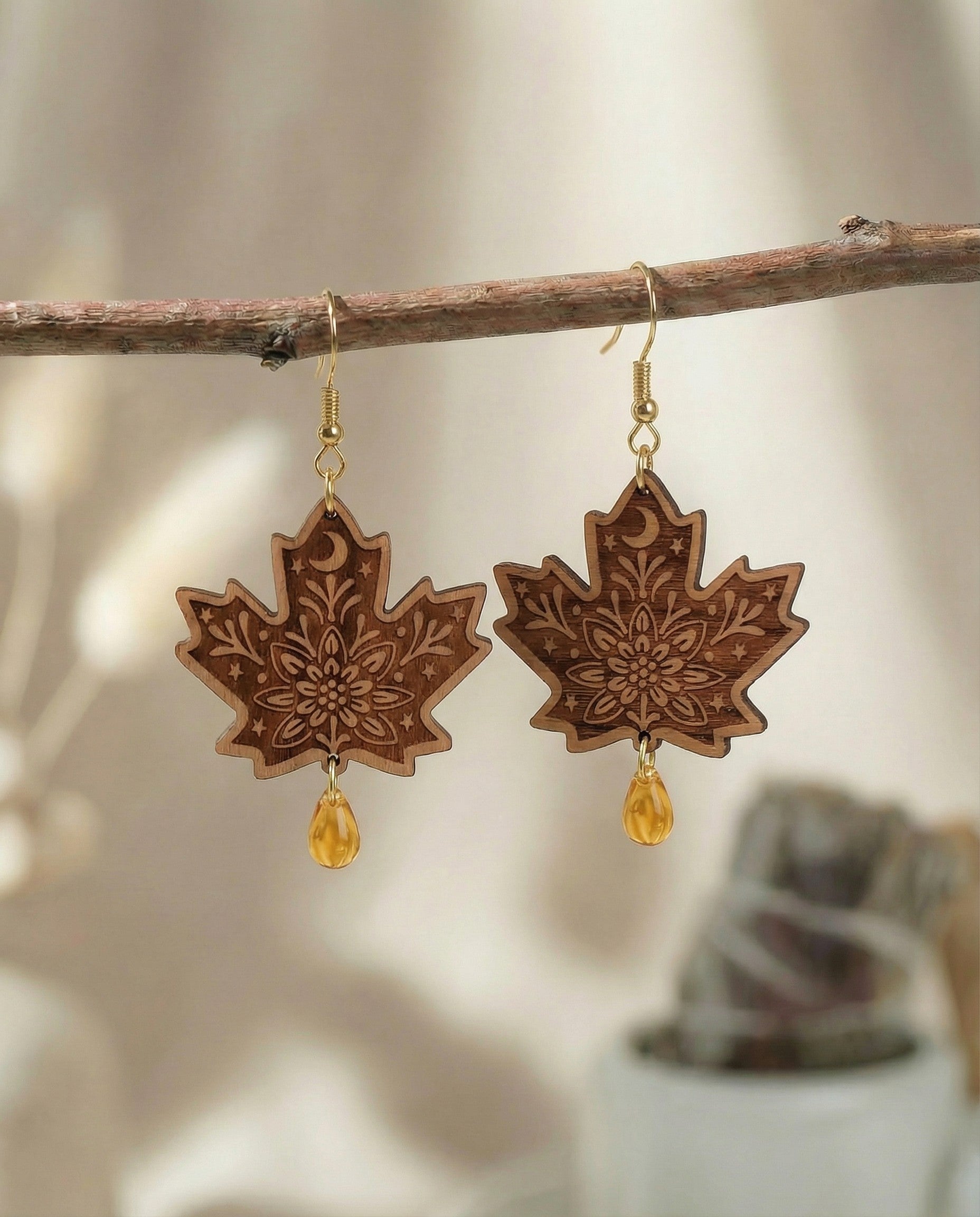 Engraved maple leaf wood dangle earrings hanging on a branch with amber Czech glass teardrop beads and 14k gold hooks.
