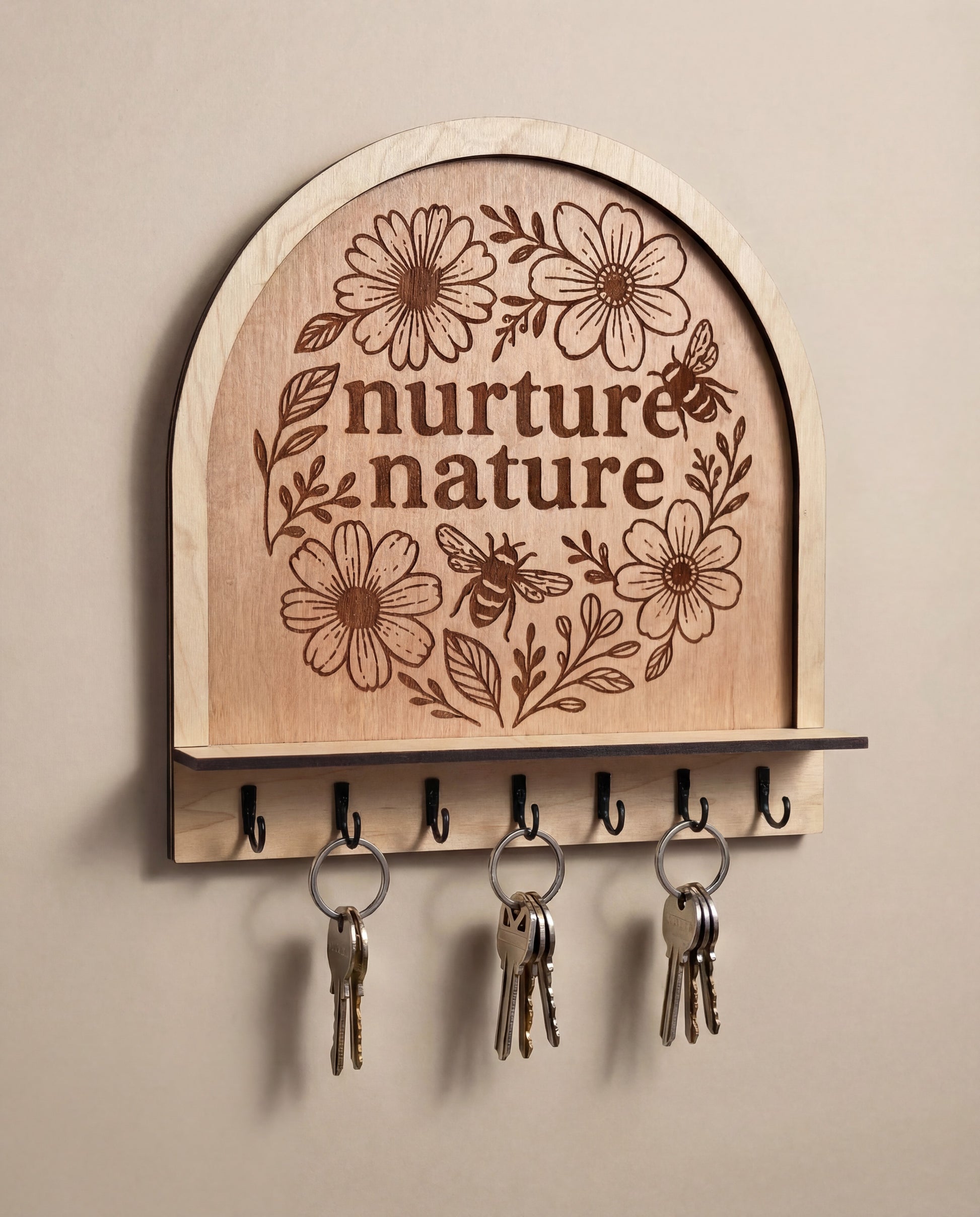 Arched wooden wall hook rack with “nurture nature” floral bee engraving and black metal hooks