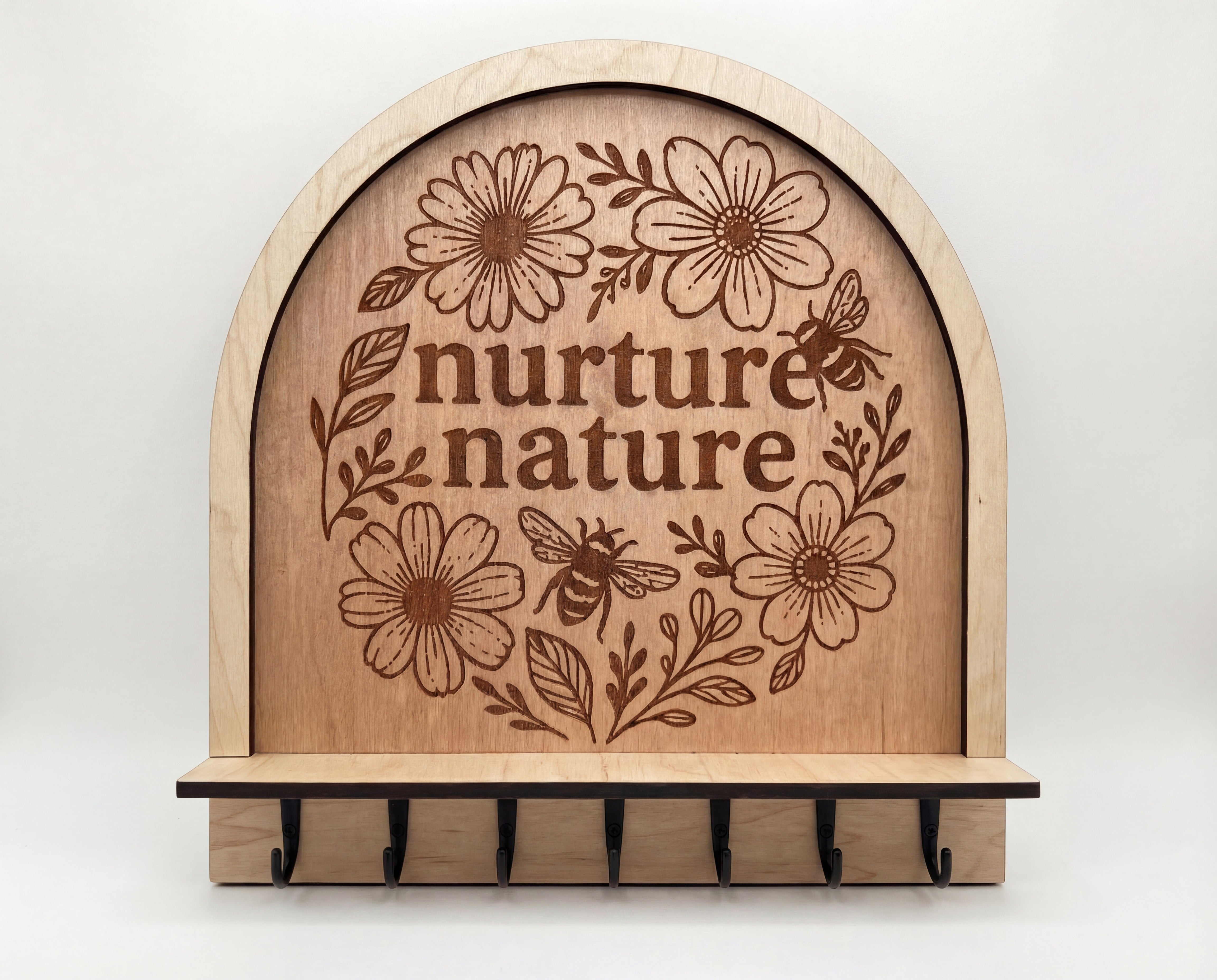 Arched wooden wall jewelry organizer with “nurture nature” floral engraving, with 7 black hooks.