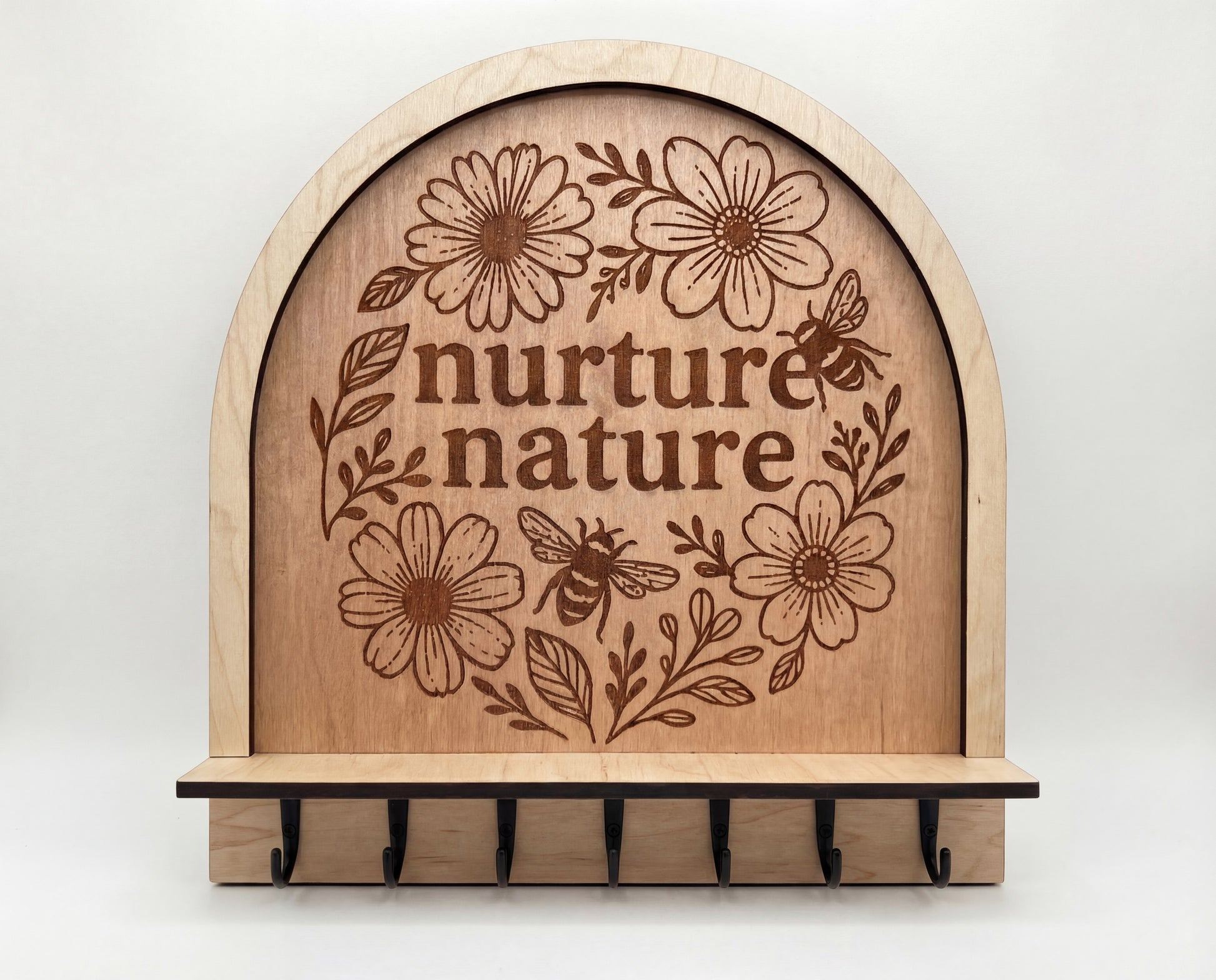 Wooden key and jewelry holder with 'nurture nature' engraving and floral designs on a white background