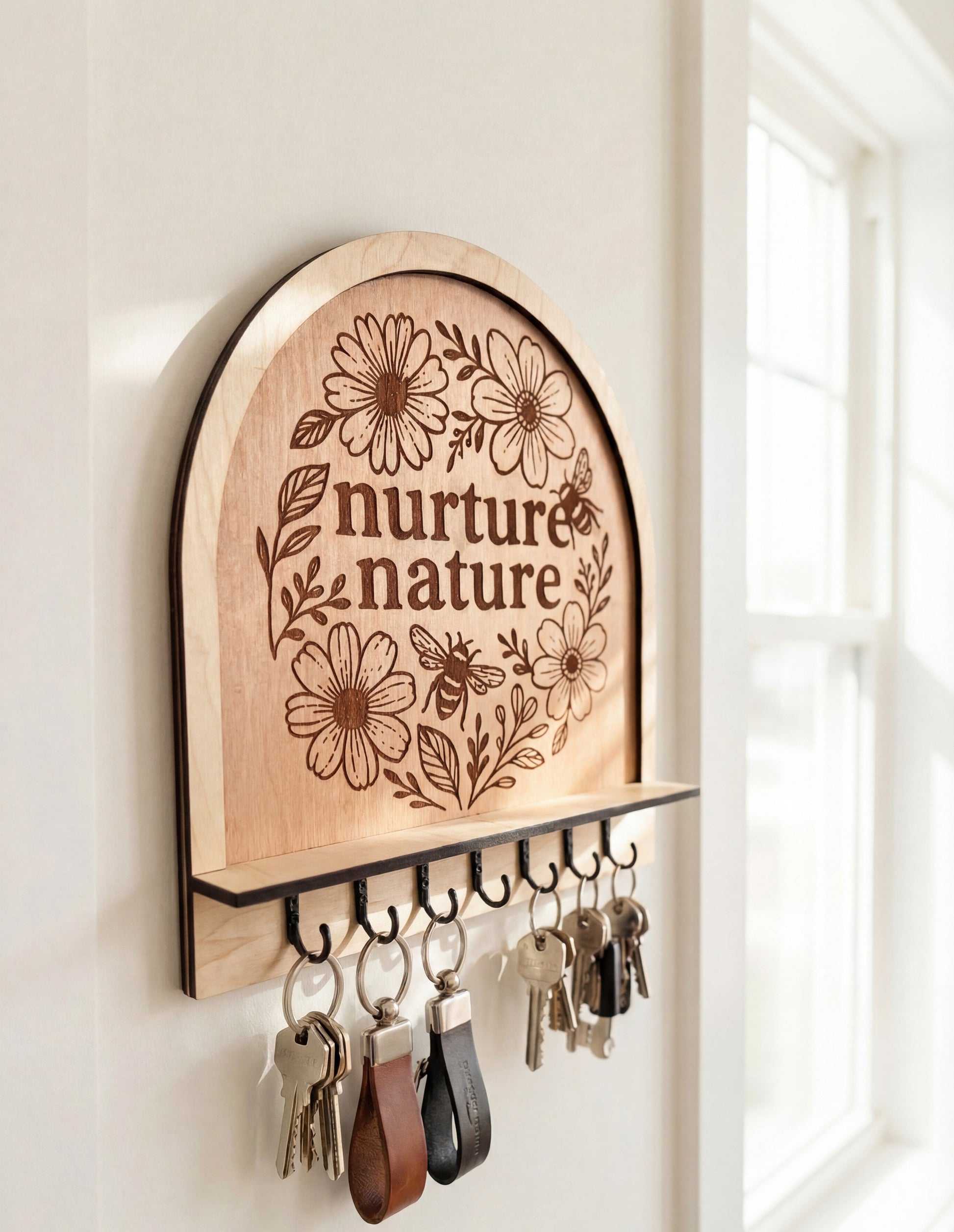 Arched wooden wall key holder with “nurture nature” floral bee engraving and hooks holding keys