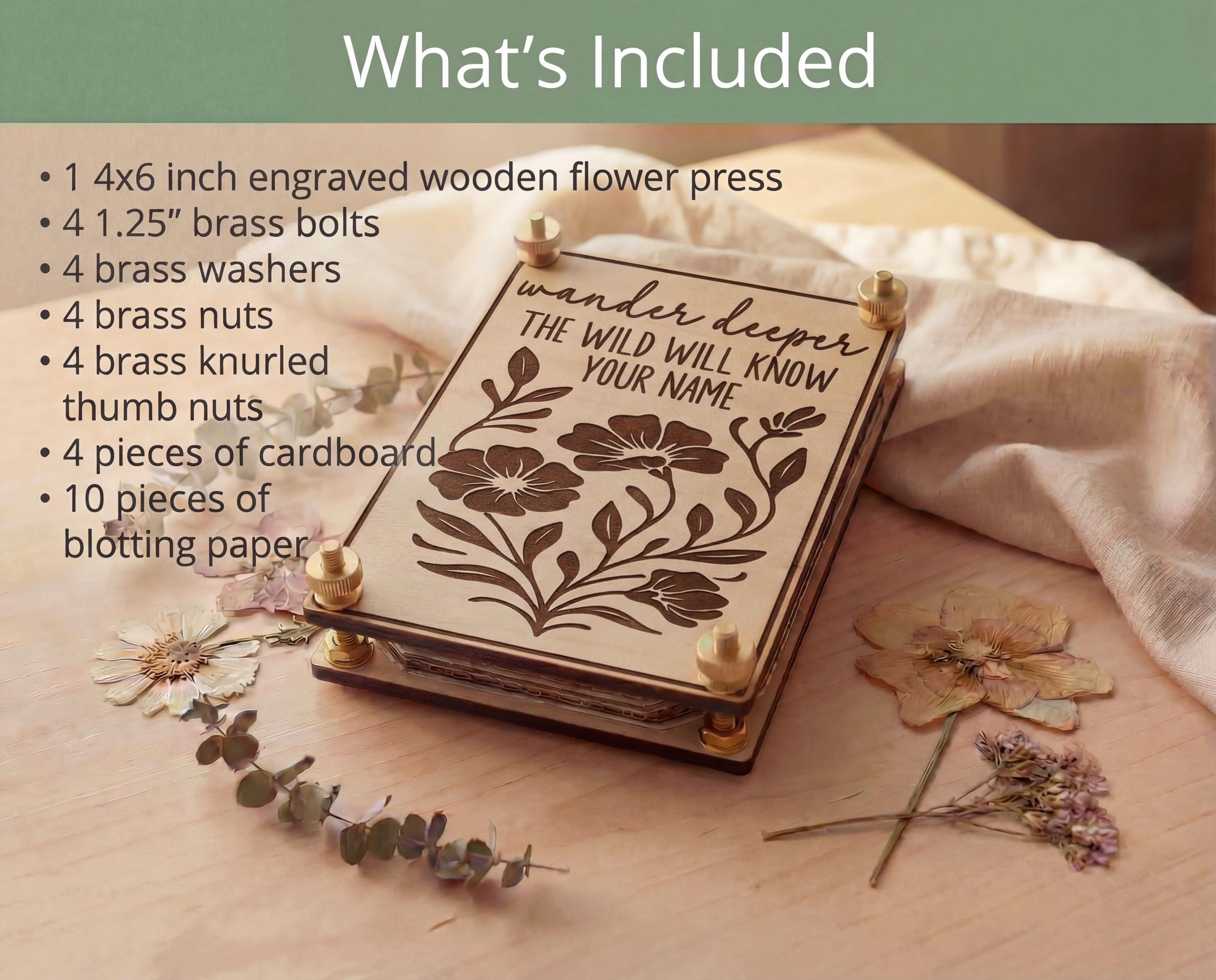 “What’s Included” graphic listing contents of a 4x6 engraved wooden flower press kit (1.25” brass bolts, washers, nuts, knurled thumb nuts, cardboard, and blotting paper) beside the maple flower press with “Wander deeper, the wild will know your name” design on a wood table with linen and pressed flowers.
