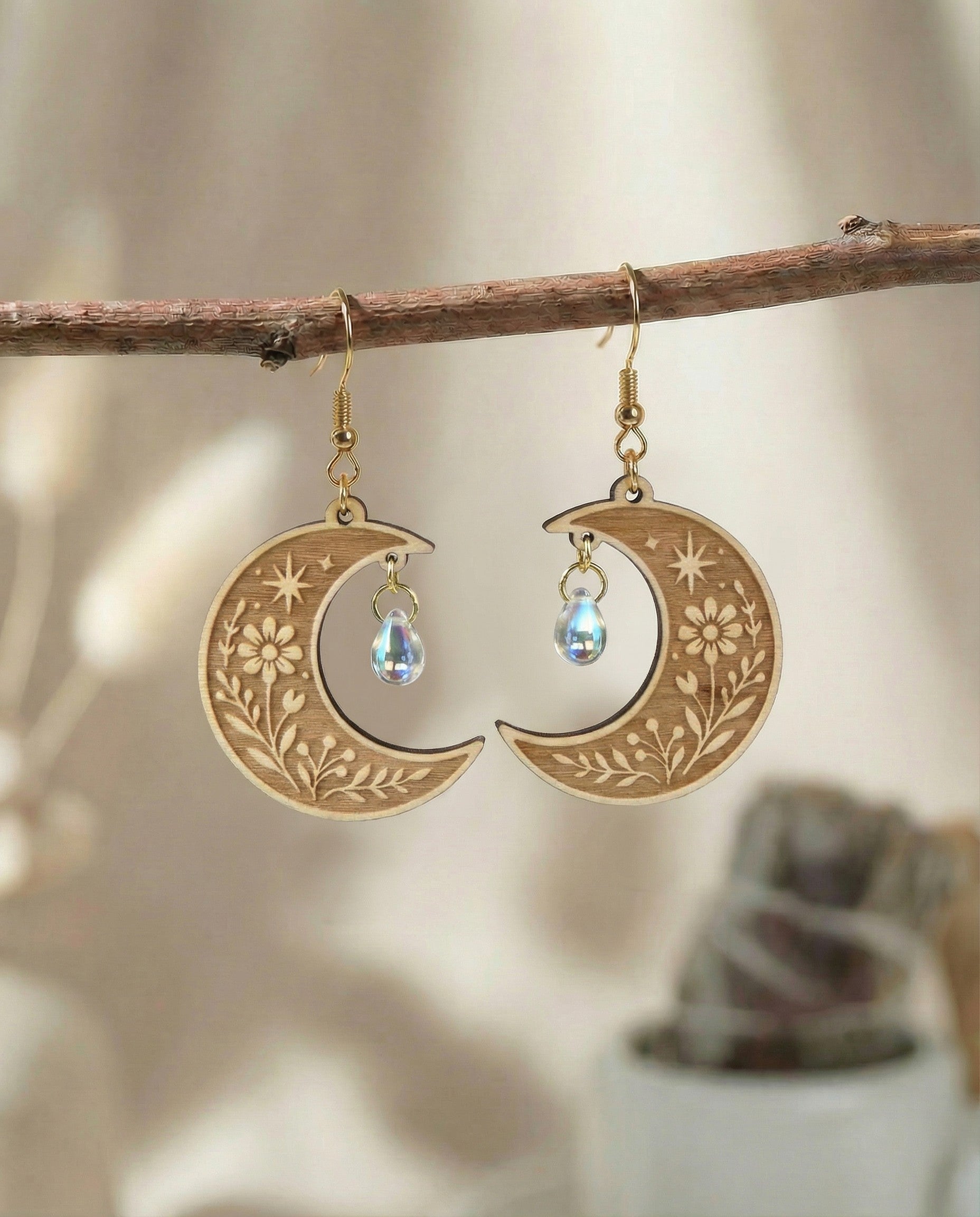 Laser engraved floral crescent moon wood earrings with 14K gold plated hooks on a branch