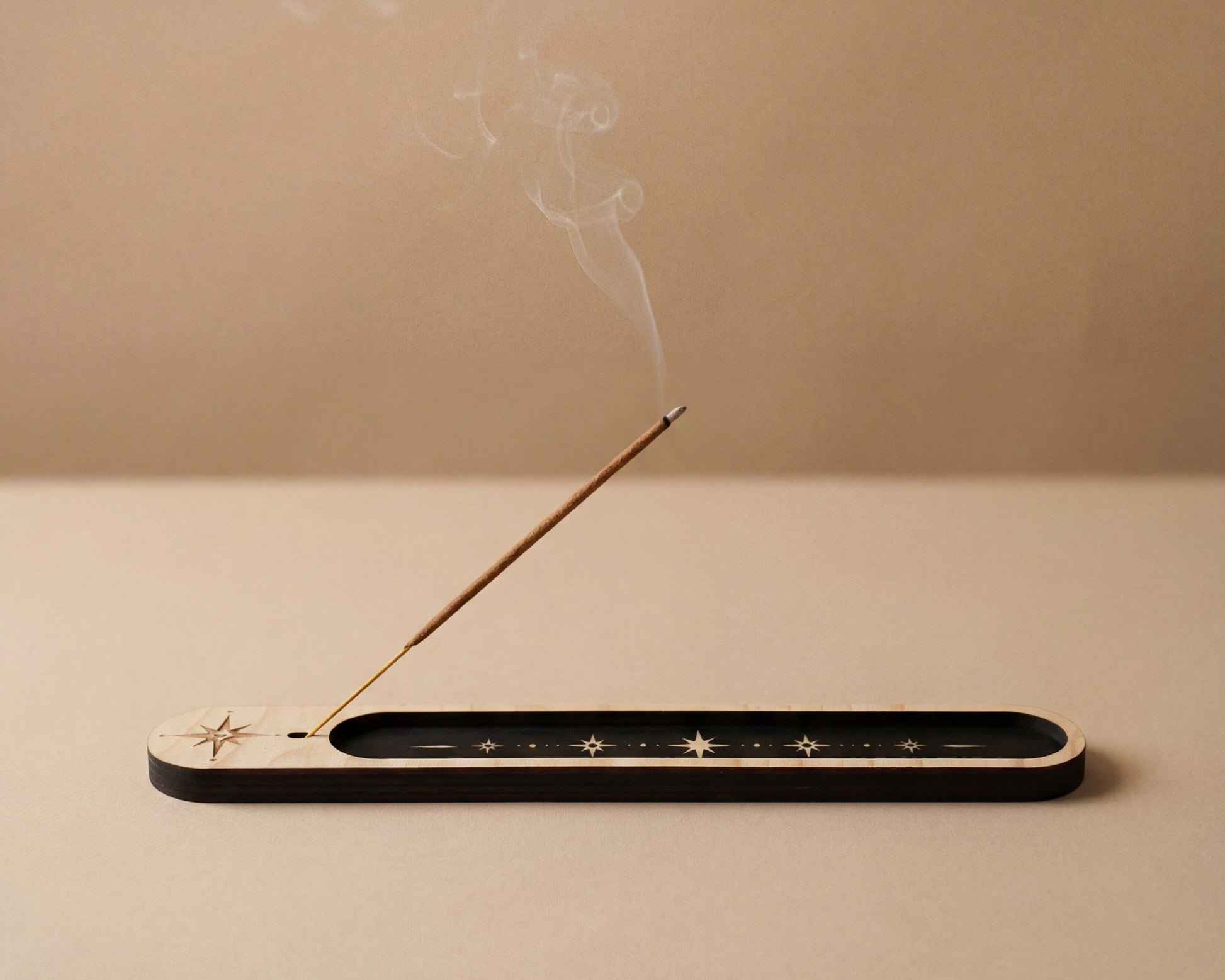 Lit incense stick resting in a slim wooden celestial incense holder with black inlay and star details, with smoke drifting upward.